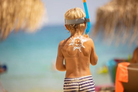 Foto de Niño feliz, rubio en la playa con protector solar aplicado, disfrutando del verano, jugando. Chalkidiki, Grecia - Imagen libre de derechos