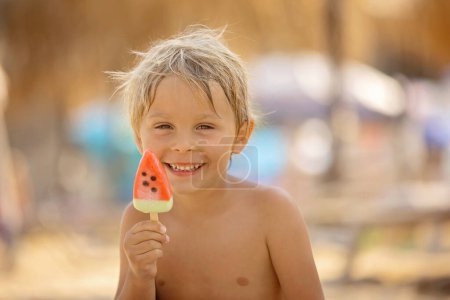 Téléchargez les photos : Happy child, boy eating ice cream  on the beach, enjoying summer, playing. Halkidiki, Greece - en image libre de droit