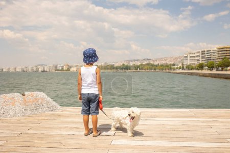 Photo for Child, visiting Thessaloniki during the summer with his pet dog and family, Greece - Royalty Free Image