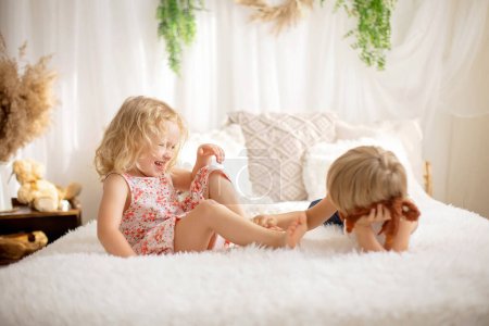 Photo for Cute sweet toddler children, tickling feet on the bed, laughing and smiling, childish mischief, happiness - Royalty Free Image