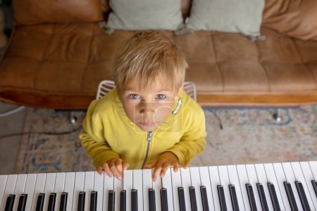 Foto de Niño, rubio, tocando el piano en casa, aprendiendo - Imagen libre de derechos