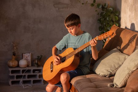 Photo for Preteen child, boy, learning how to play acoustic guitar at home, sunny room - Royalty Free Image