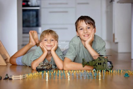 Photo for Happy children, siblings, boy, playing with tanks and soldiers at home. Bautirufl kids playing with plastic toys - Royalty Free Image