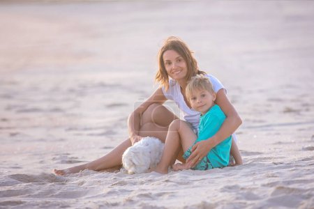 Téléchargez les photos : Enfants heureux, garçons, jouant sur la plage au coucher du soleil, enfant couvert de sable, souriant, riant, appréciant un peu de plaisir - en image libre de droit