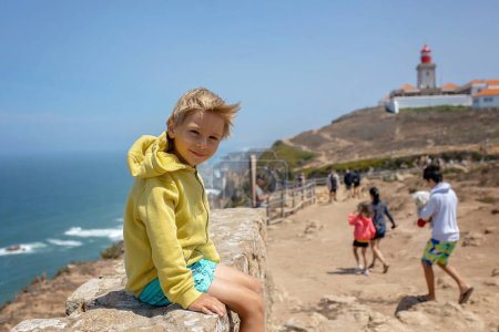 Foto de Familia con niños, hermanos, visitando el punto más occidental de Europa, Cabo Da Roca, durante las vacaciones familiares de verano en Portugal - Imagen libre de derechos