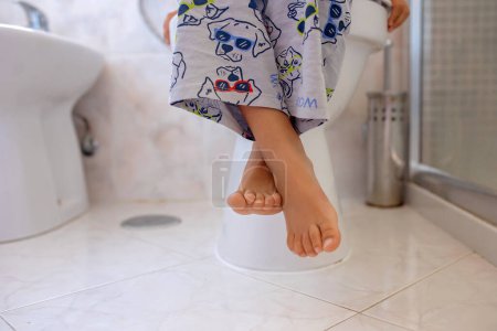 Photo for Cute child, boy, sitting on the toilet in bathroom - Royalty Free Image