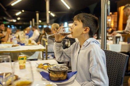 Foto de Niño lindo, chico, comer pescado para la cena en un restaurante en Portugal, verano - Imagen libre de derechos