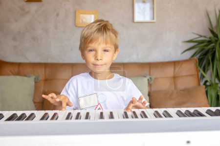 Téléchargez les photos : Enfant, garçon blond, jouer du piano à la maison, apprendre - en image libre de droit