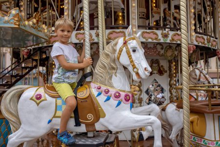 Téléchargez les photos : Enfants, garçons, allez sur Merry Go Round, les enfants jouent sur carrousel été à Strasbourg, France pendant les vacances d'été - en image libre de droit