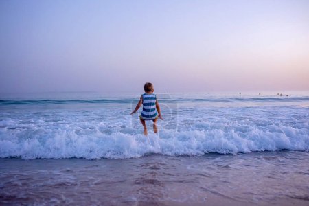Téléchargez les photos : Enfants heureux, jouant sur la plage au coucher du soleil, enfants courant dans l'eau dans l'océan, enfance heureuse - en image libre de droit