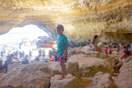 Photo for Children, enjoying Benagil, Portugal. Benagil Cave inside Algar de Benagil, famous sea cave in Algarve coast, Lagoa. Happy family on a canoe trip - Royalty Free Image