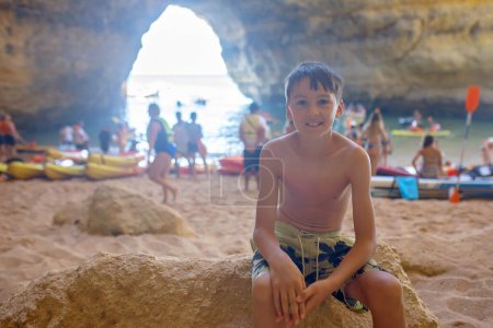 Foto de Niños, disfrutando de Benagil, Portugal. Cueva de Benagil dentro del Algar de Benagil, famosa cueva marina en la costa del Algarve, Lagoa. Familia feliz en un viaje en canoa - Imagen libre de derechos