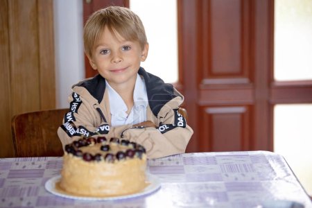 Téléchargez les photos : Mignon enfant d'âge préscolaire, soufflant des bougies sur son gâteau, six ans, allant à l'école. Enfant prêt pour le premier jour à l'école - en image libre de droit