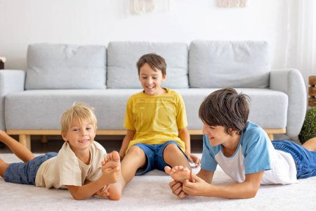 Photo for Happy positive children, tickling on the feet, having fun together, boy brothers at home having wonderful day of joy together - Royalty Free Image