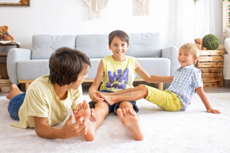 Photo for Happy positive children, tickling on the feet, having fun together, boy brothers at home having wonderful day of joy together - Royalty Free Image