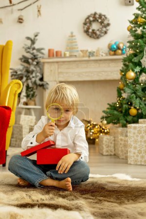 Téléchargez les photos : Enfant mignon, garçon, jouer dans une chambre décorée pour Noël, endroit confortable - en image libre de droit