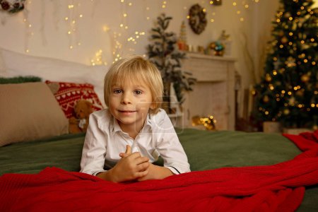 Téléchargez les photos : Enfant mignon, garçon, jouer dans une chambre décorée pour Noël, endroit confortable - en image libre de droit