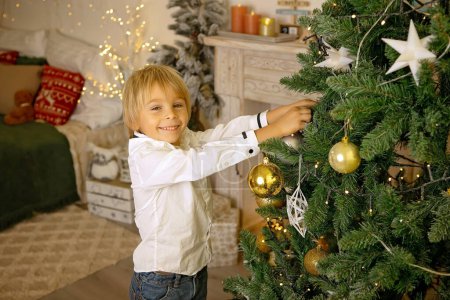 Foto de Lindo niño, niño, jugando en una habitación decorada para Navidad, lugar acogedor - Imagen libre de derechos
