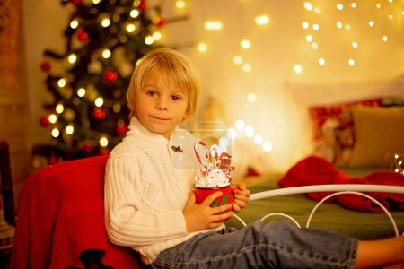 Téléchargez les photos : Enfant mignon, garçon, assis sur un fauteuil jaune dans une chambre décorée pour Noël, endroit confortable - en image libre de droit
