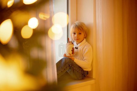 Photo for Cute child, boy, sitting on a yellow armchair in a decorated room for Christmas, cozy place - Royalty Free Image