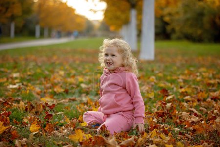 Foto de Lindos niños rubios niño y niña, caminando en el parque de otoño al atardecer, disfrutando de la hermosa naturaleza, otoño - Imagen libre de derechos