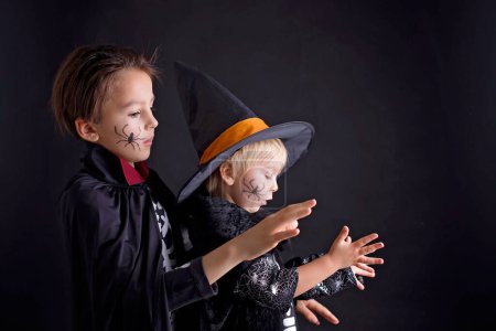 Foto de Niños. hermanos, vestidos para Halloween, jugando en casa, imagen aislada en negro - Imagen libre de derechos