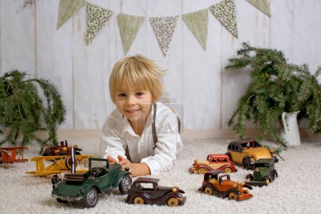 Foto de Dulce niño rubio, jugando con coches y aviones en casa, niño lindo de moda - Imagen libre de derechos
