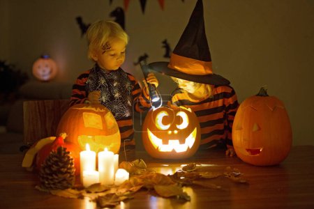 Foto de Niños, hermanos, jugando con calabaza tallada en casa en Halloween - Imagen libre de derechos