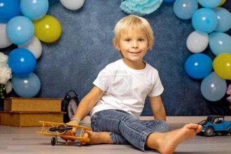 Photo for Cute preschool boy, playing with airplane, balloons and birthday decoration in the background - Royalty Free Image