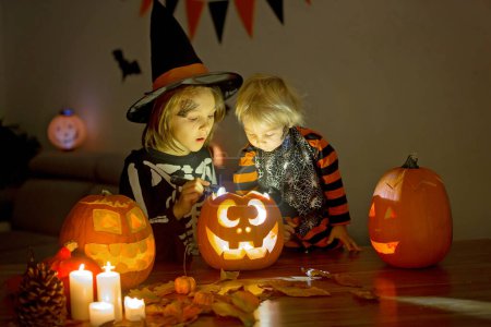 Photo for Children, boy brothers, playing with carved pumpkin at home on Halloween, making magic potion - Royalty Free Image