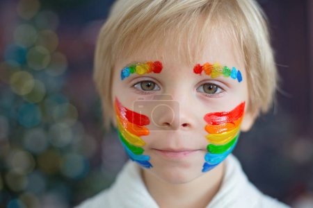 Foto de Hermoso niño, niño pequeño con la cara pintada con arco iris, posando para retrato cercano en el estudio - Imagen libre de derechos
