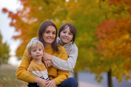 Photo for Happy family, mother with children, having their autumn pictures taken in the park, children playing - Royalty Free Image
