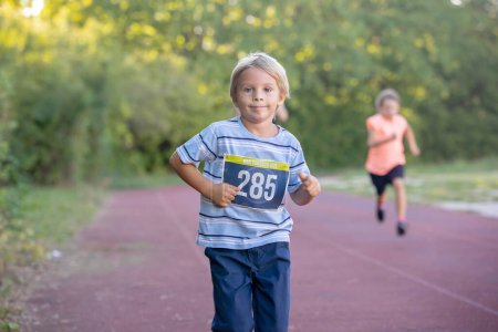 Foto de Niños preescolares, corriendo en pista en una competencia de maratón en el parque - Imagen libre de derechos