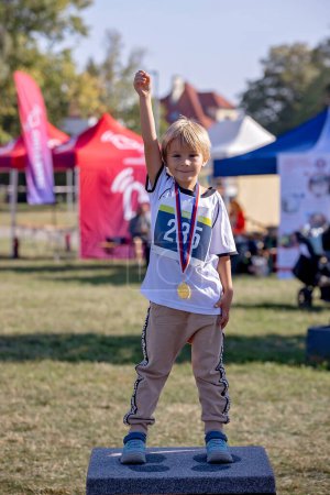 Photo for Young preschool children, running on track in a marathon competition in the park - Royalty Free Image