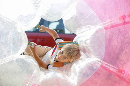Foto de Niño lindo, niño preescolar, jugando en la bola inflable en el parque, disfrutando del día soleado - Imagen libre de derechos