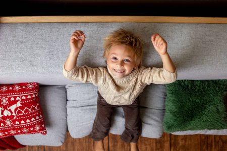 Téléchargez les photos : Belle enfant blonde, jeune écolier, jouant dans une maison décorée avec des jouets tricotés à Noël - en image libre de droit