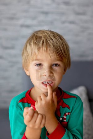 Foto de Dulce niño rubio preescolar, chico, perdiendo su primer diente de leche, sonriendo felizmente, sosteniendo el pequeño diente en su mano - Imagen libre de derechos