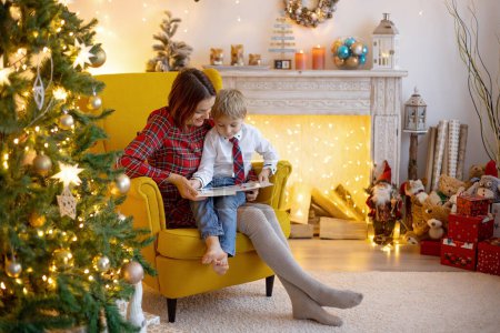 Téléchargez les photos : Maman et enfant, mignon garçon blond, assis à la maison dans un fauteuil confortable, profiter de temps en famille de qualité ensemble - en image libre de droit