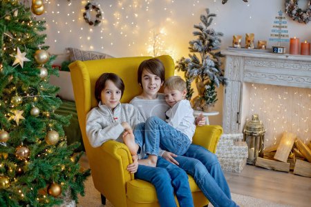 Foto de Cuadro familiar de Navidad en casa acogedora con luces y decoración, abuela, madre e hijos - Imagen libre de derechos