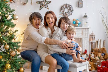 Téléchargez les photos : Photo de famille de Noël dans une maison confortable avec lumières et décoration, grand-mère, mère et enfants - en image libre de droit