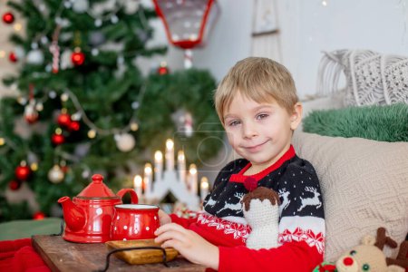 Foto de Small toddler child, lying sick in bed, red eyes, drinking tea on christmas at home - Imagen libre de derechos