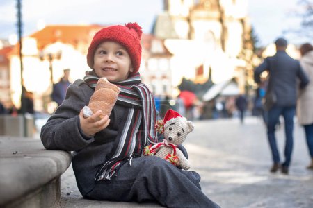 Photo for Child in Prague on Christmas, eating traditional czech dessert trdelnik in the city center - Royalty Free Image