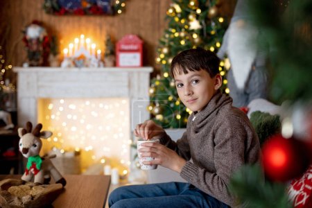 Téléchargez les photos : Belle enfant blonde, jeune écolier, jouant dans une maison décorée avec des jouets tricotés à Noël - en image libre de droit