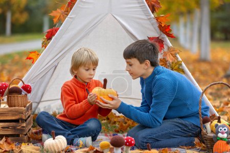 Foto de Lindos niños felices, hermanos, niños, jugando con juguetes de punto en el parque, otoño, setas, hojas, calabazas - Imagen libre de derechos