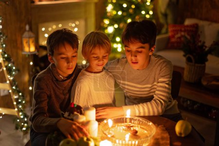 Foto de Tres niños, encendiendo velas en pocas palabras, tradiciones navideñas checas, habitación decorada, tradiciones familiares - Imagen libre de derechos