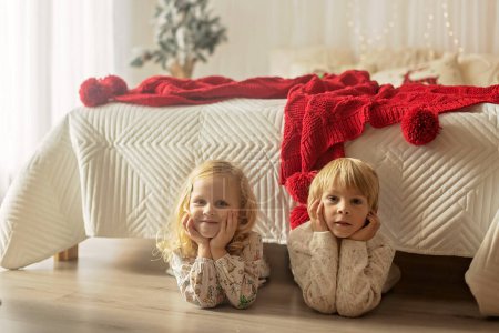 Téléchargez les photos : Beaux enfants, enfants blonds, frères et sœurs, jouer dans la maison décorée pour Noël, profiter des vacances à la maison - en image libre de droit