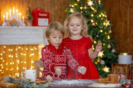 Téléchargez les photos : Beaux enfants, enfants blonds, frères et sœurs, jouer dans la maison décorée pour Noël, profiter des vacances à la maison - en image libre de droit