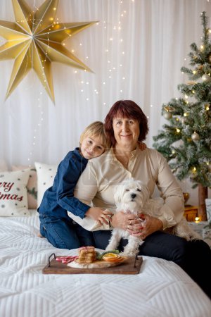 Téléchargez les photos : Grand-mère et enfant à la maison à Noël, lecture, lettre d'écriture, cuisson, profiter des vacances de Noël - en image libre de droit