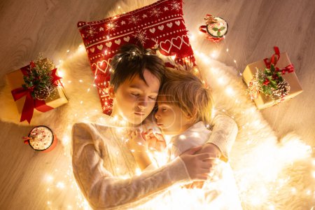 Photo for Sweet amazing cute children, boy brothers, hugging at home in front of the fireplace on Christmas, love in family - Royalty Free Image