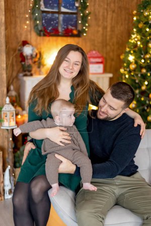 Foto de Lindo niño recién nacido, bebé, con mamá y papá en Navidad en casa, disfrutando de las primeras vacaciones de Navidad - Imagen libre de derechos